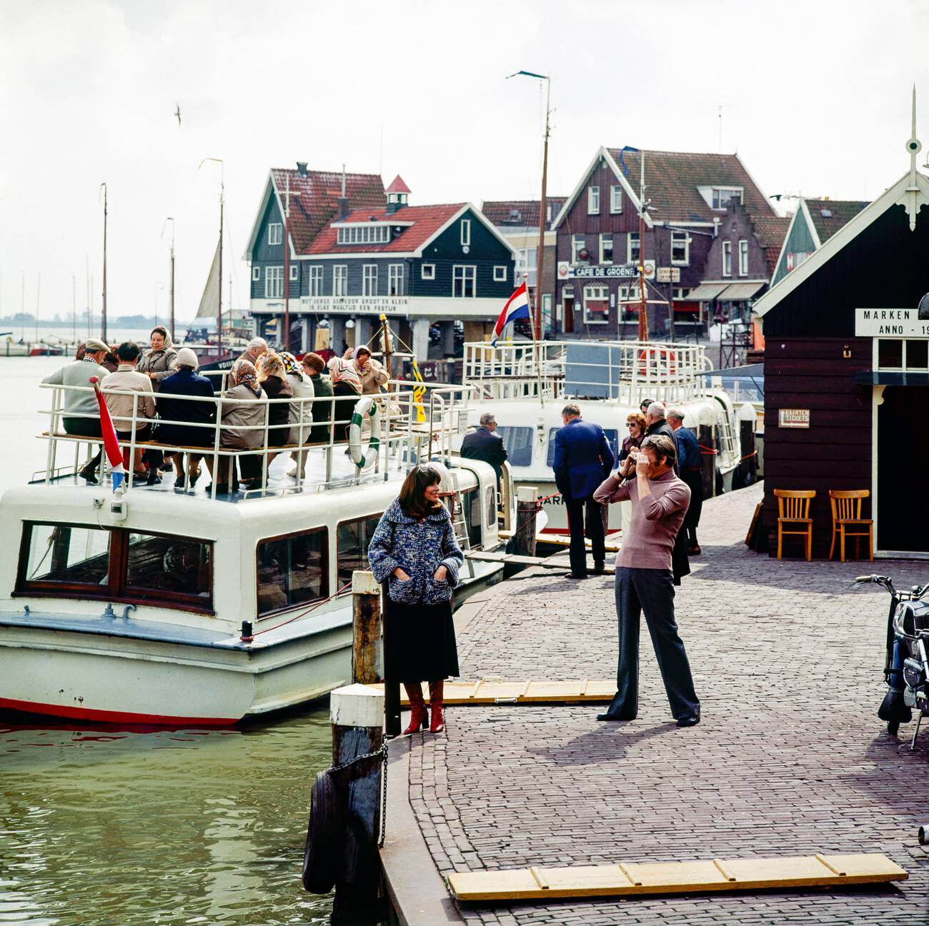 A couple of middle-aged tourists taking pictures at Marken harbor, Waterland, Northern Holland, The Netherlands in the 1970s.