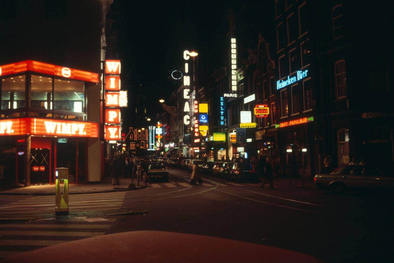 Neon lights at night in the city center of Amsterdam, The Netherlands, during the 1970s-1980s. Wimpy fast food takeaway restaurant is visible.