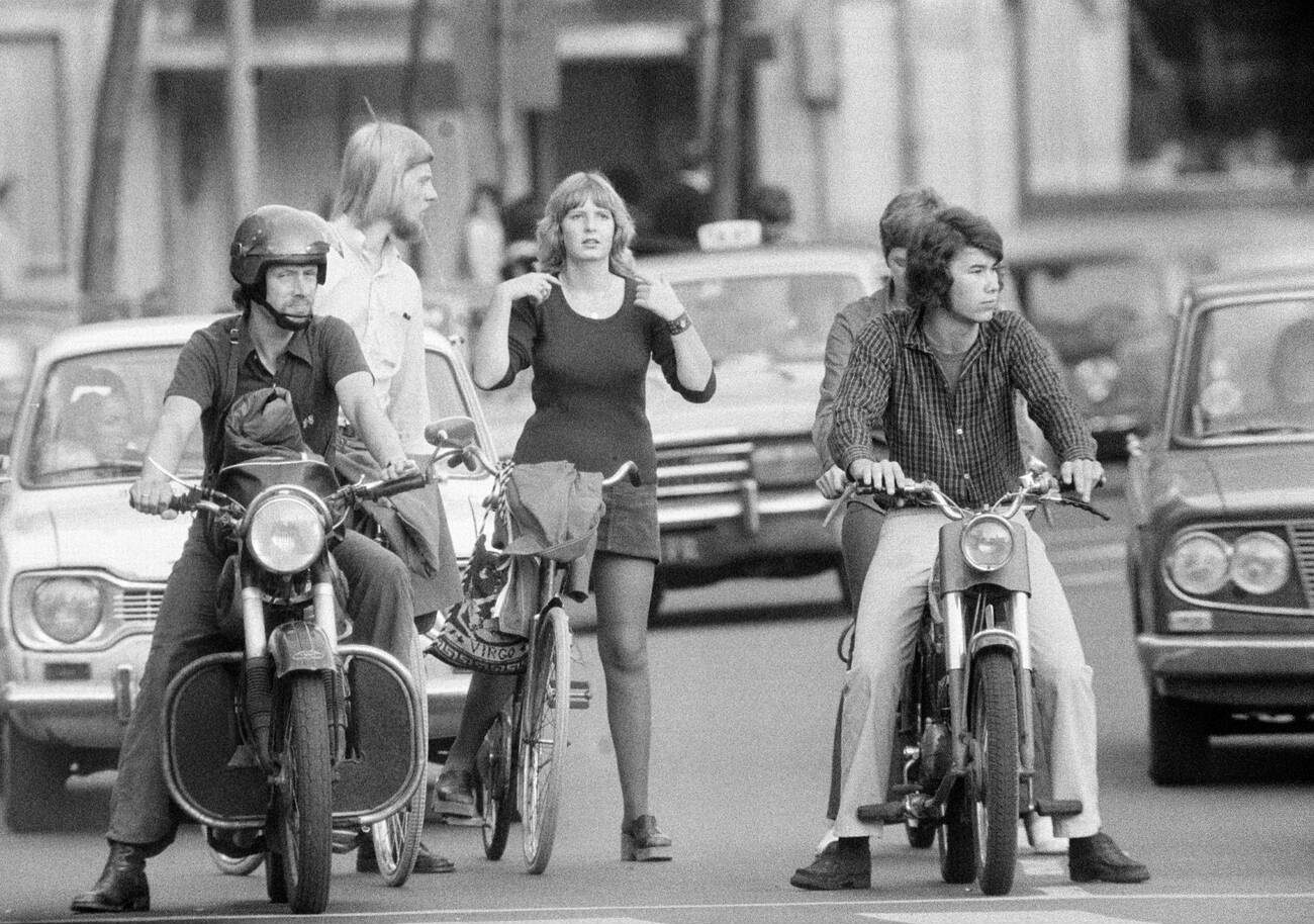 Road traffic in Amsterdam, 1970s: A black and white photograph capturing different types of traffic users waiting at red lights in Amsterdam, in the 1970s.
