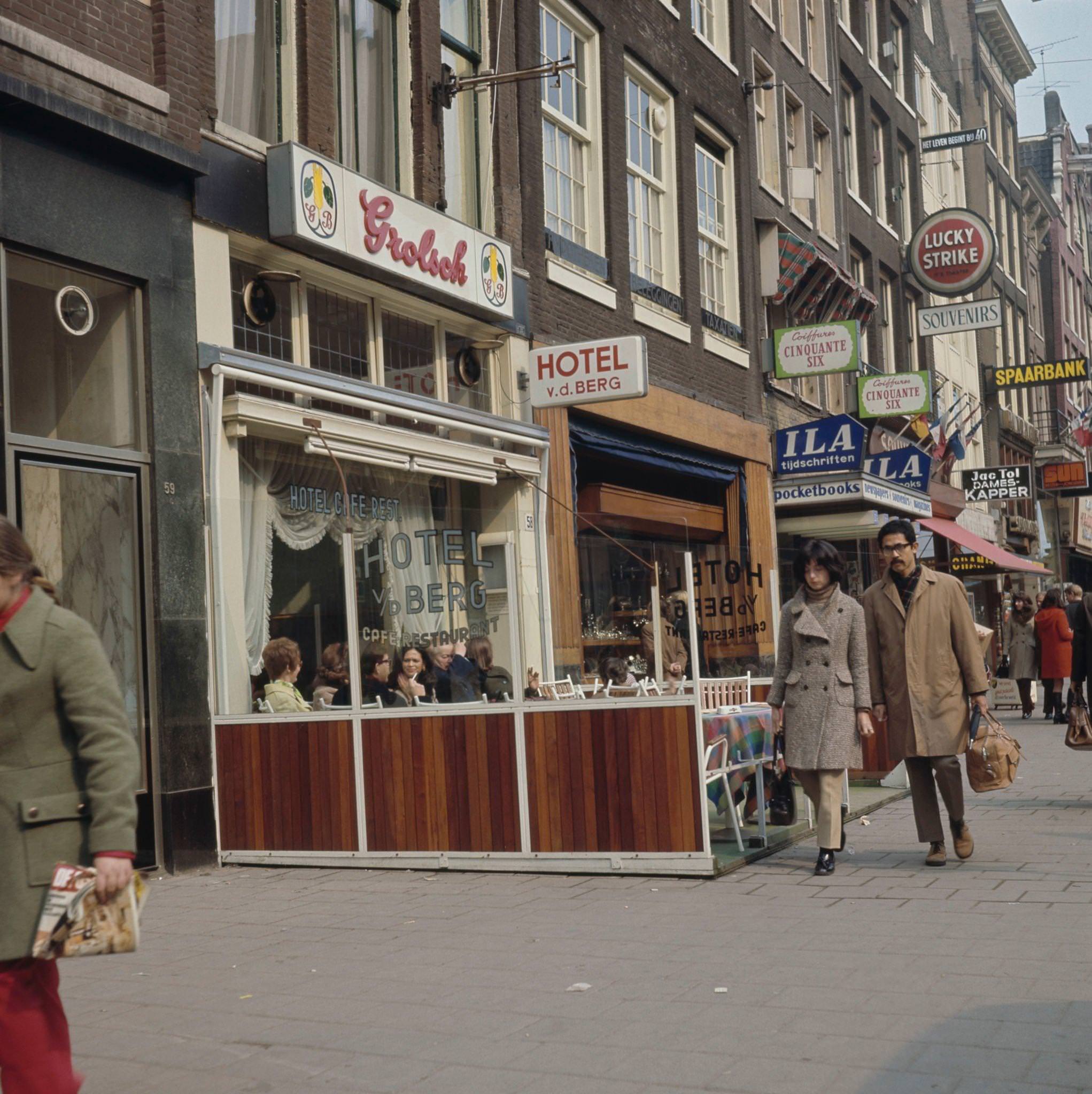 Pedestrians walk past diners seated at tables outside a cafe and restaurant on a street in the center of Amsterdam, capital city of the Netherlands, 1970.