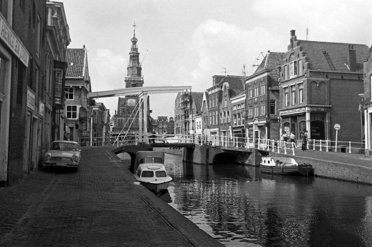 A picture of a canal with the historical De Waag building in the background in Alkmaar, The Netherlands in 1971.