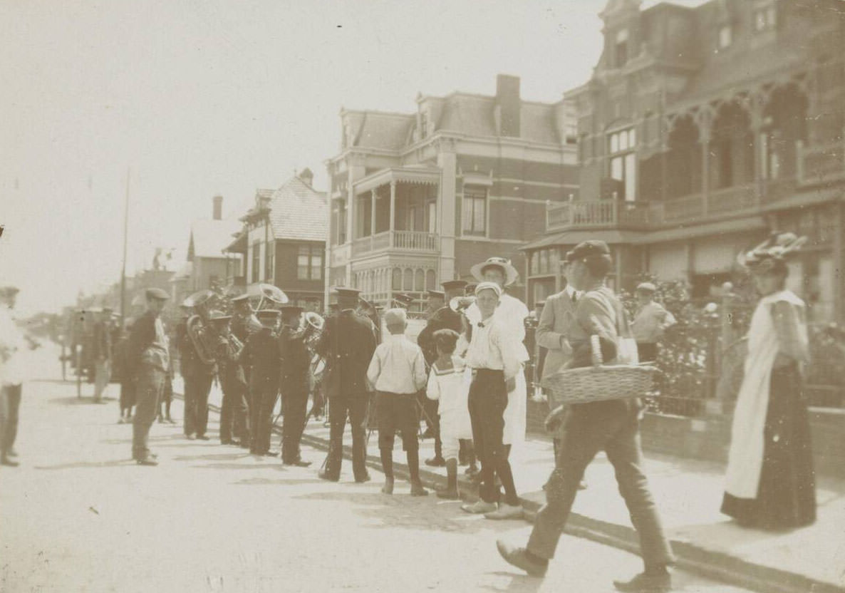 Street scene with brass band in coastal town, 1900s