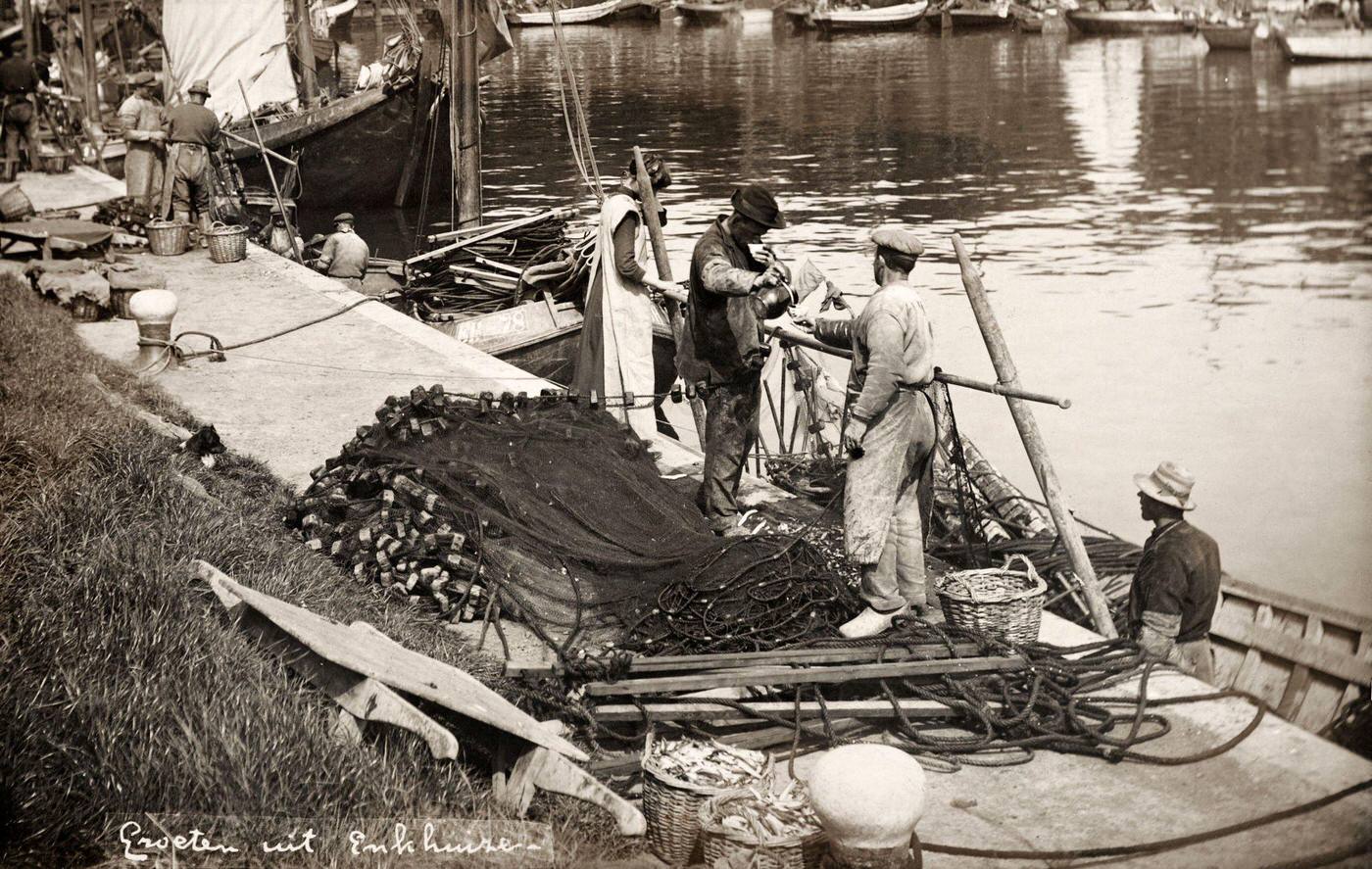 Vintage postcard of anchovy fishermen mending their nets at Enkhuizen, Netherlands, 1905