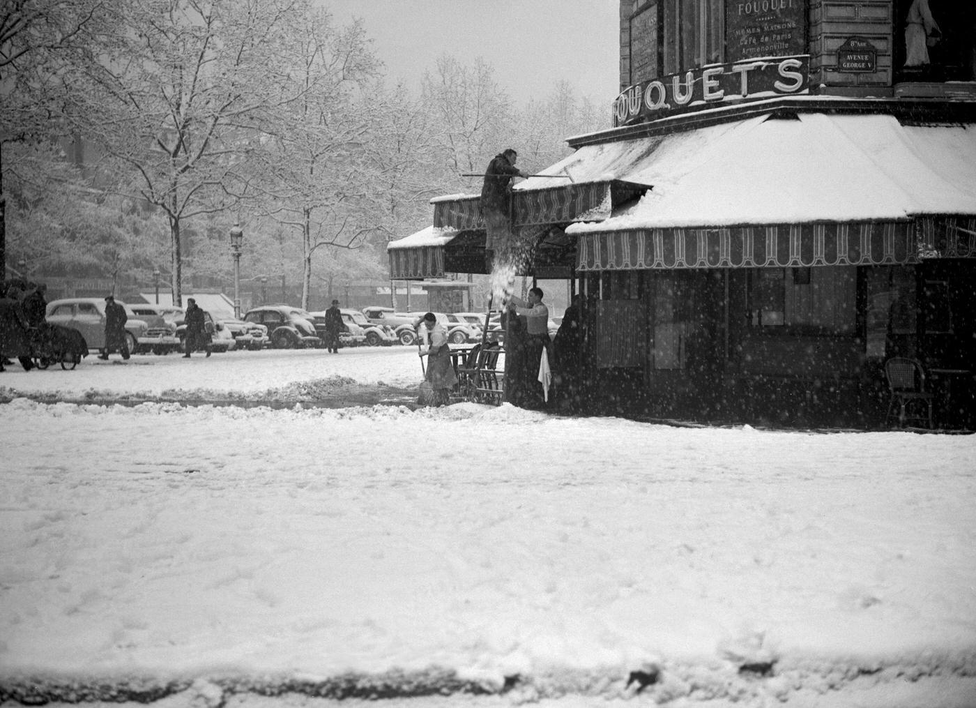 People Brushing The Snow From The Fouquet's Awning, Paris, During The 1952 Winter.