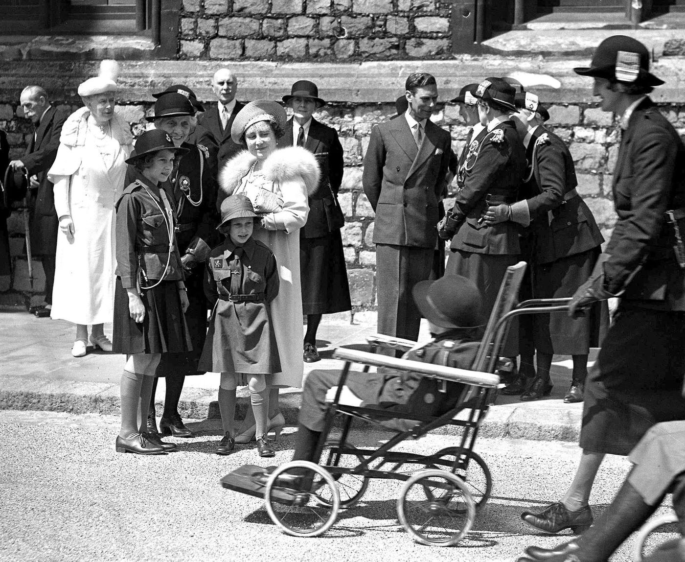 Princess Elizabeth, later Queen Elizabeth II, and Princess Margaret with the King and Queen reviewing girl guides at a Windsor castle rally.