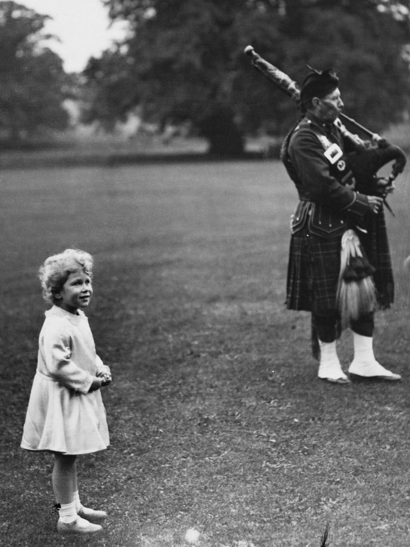 Princess Elizabeth watches members of a pipe band play in the grounds of Glamis Castle near Forfar in Scotland in September 1929.