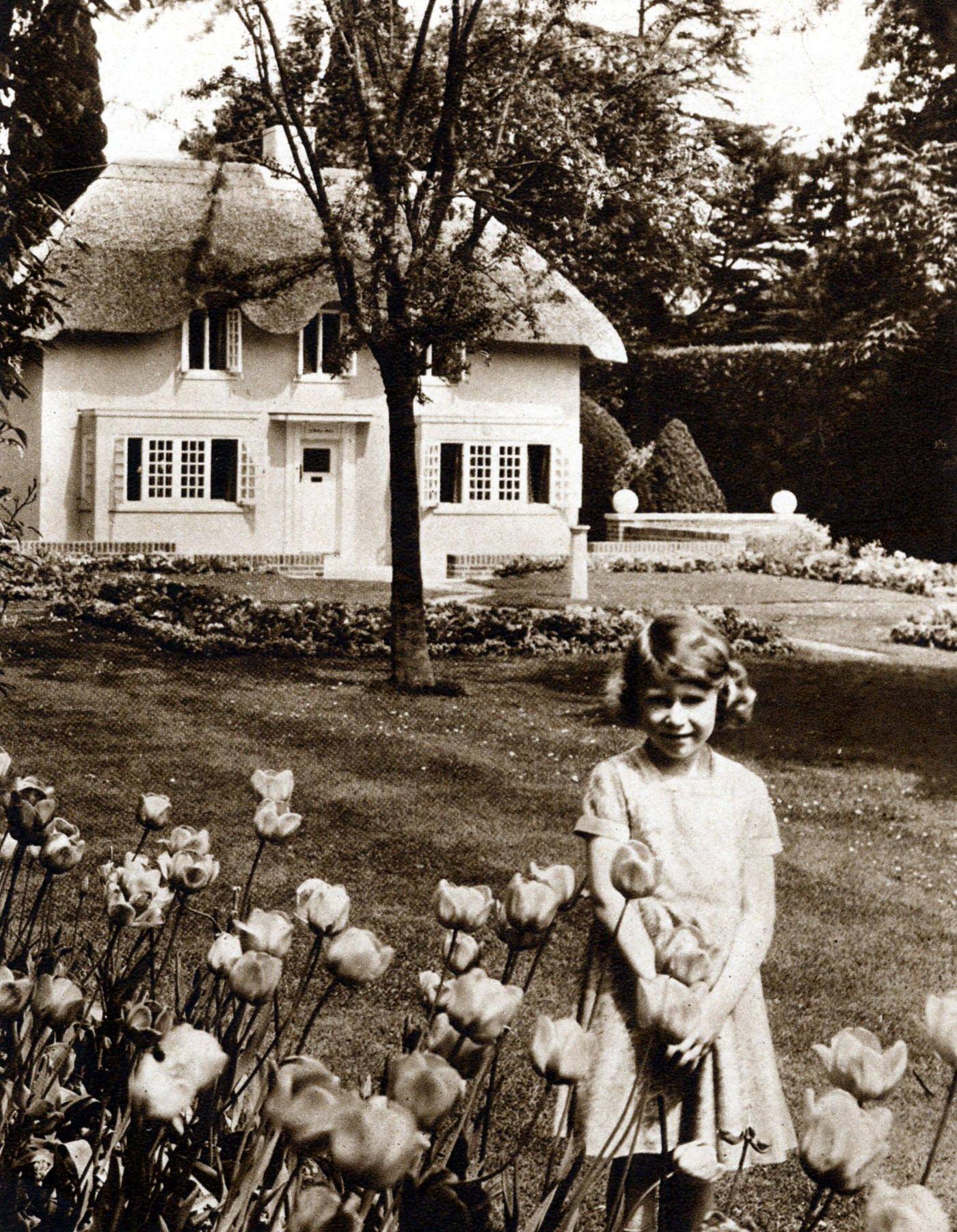 Princess Elizabeth as a child in the garden of the Royal Lodge, Windsor with Y Bwthyn Bach (The Little House), the playhouse given to her by the people of Wales.