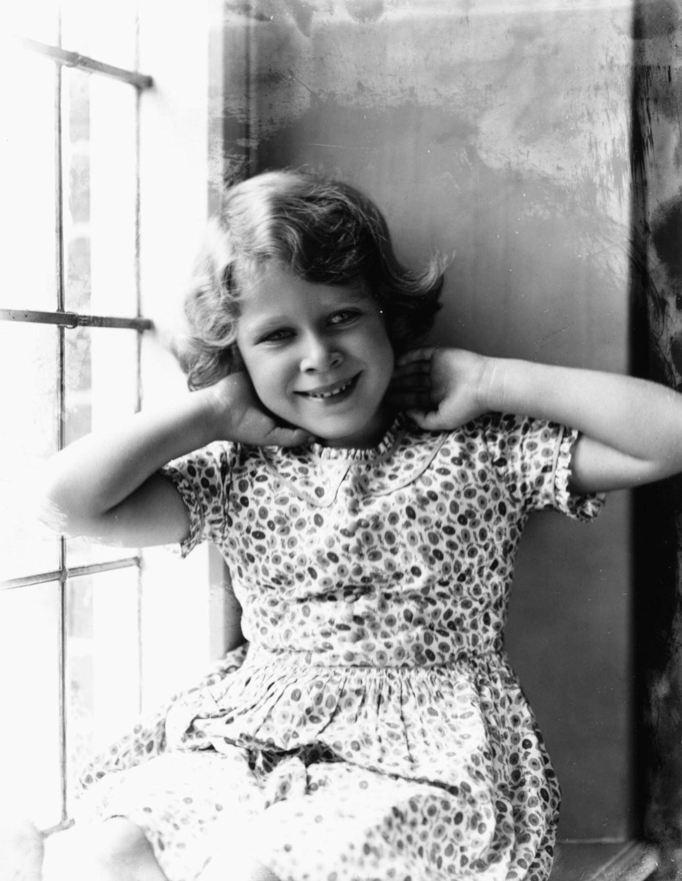 Childhood portrait of Queen Elizabeth II sitting in a window, August 12th 1932.