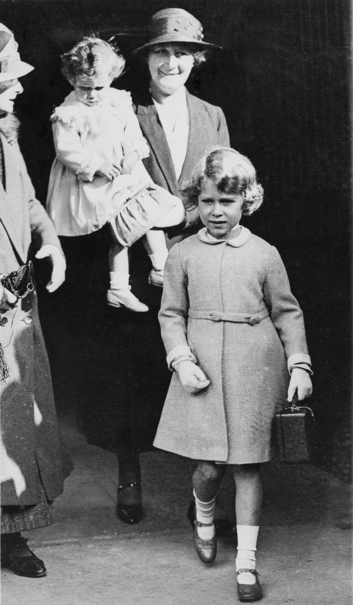 Princess Elizabeth and Princess Margaret arrive at Ballater railway station in Aberdeenshire, Scotland on August 21, 1932. Princess Elizabeth carries her own little attache case while Princess Margaret is in the arms of royal nanny Clara Knight.