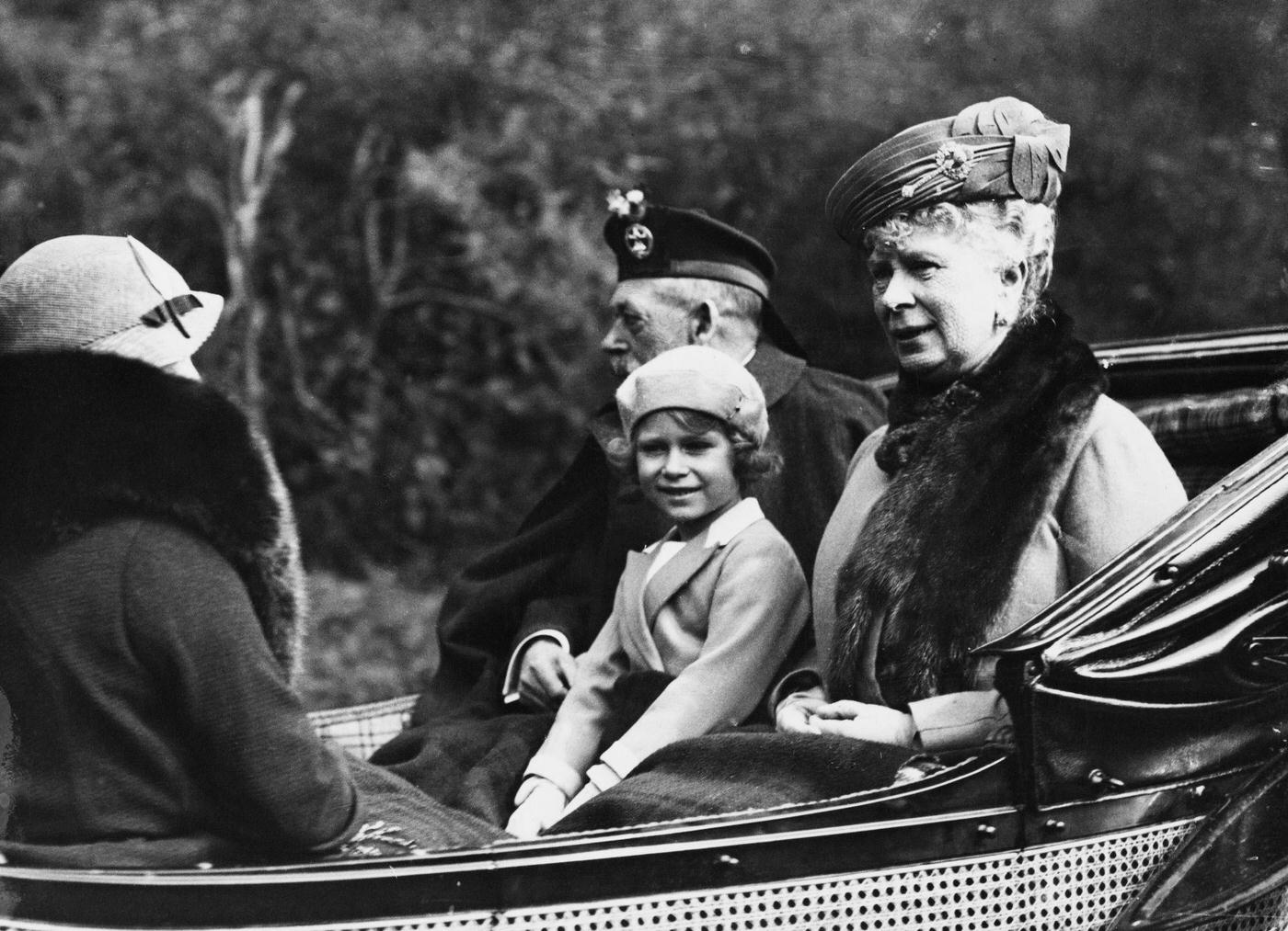 Princess Elizabeth seated between her grandfather King George V and grandmother Queen Mary of Teck as they ride in a carriage back to Balmoral Castle from Crathie Kirk near Braemar in Scotland in August 1935.