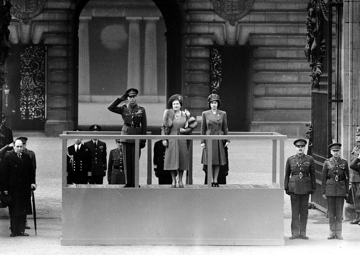 King George VI and Queen Elizabeth accompanied by Princess Elizabeth on the saluting base at Buckingham Palace, as the "Salute the Soldier" parade marches by.
