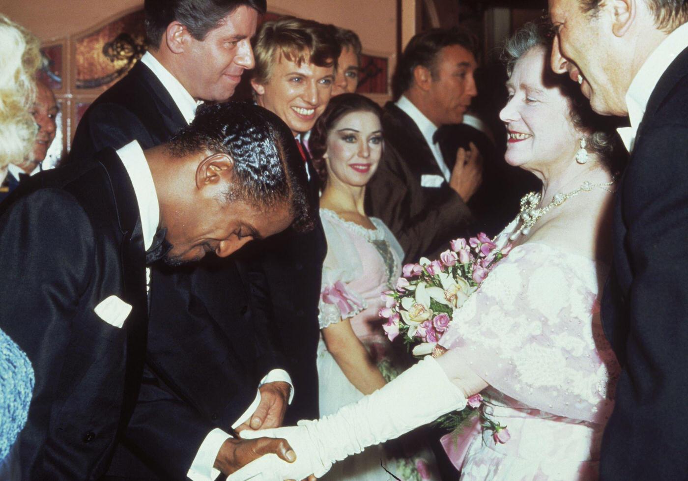 The Queen Mother shakes hands with Sammy Davis Jr., Jerry Lewis, and Tommy Steele backstage at the Royal Variety Show, 1966.