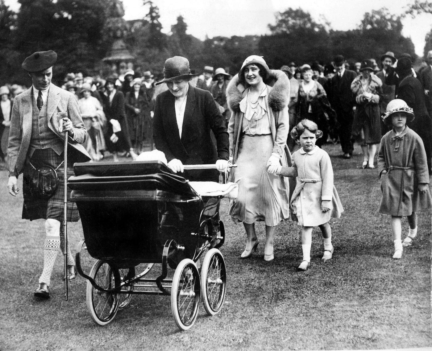 King George VI and Queen Elizabeth with Princesses Elizabeth and Margaret in a pram at a garden party, 1931.