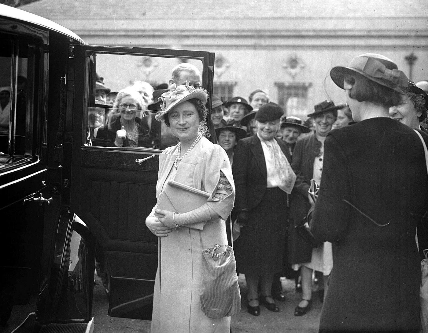 Queen Elizabeth carrying both her handbag and gas mask after visiting the Woodford, Essex Clearing House of the central hospital supply service during WWII, May 24, 1940.