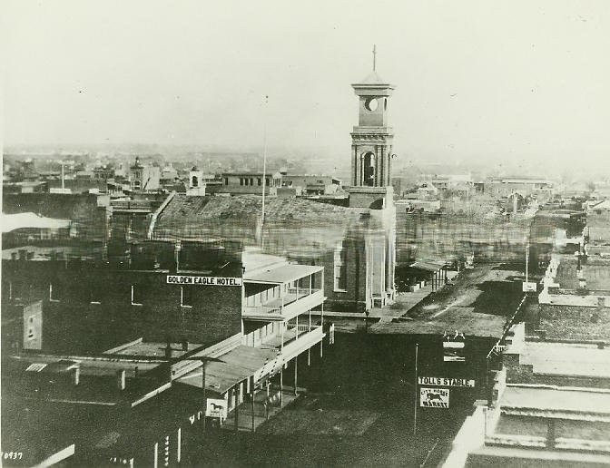 Elevated view looking down K St. from 7th. Golden Eagle Hotel and St. Rose of Lima Catholic Church to left. Toll's Stable and the City Horse Market to right, 1890