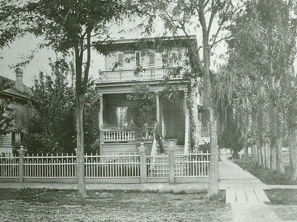 Exterior view a two-story Victorian house with fenced yard, 1890