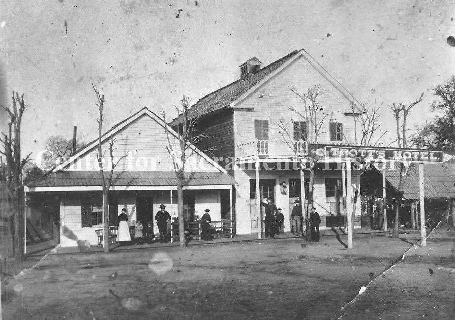 View of several people standing on front porch of Trott's Hotel, 1890