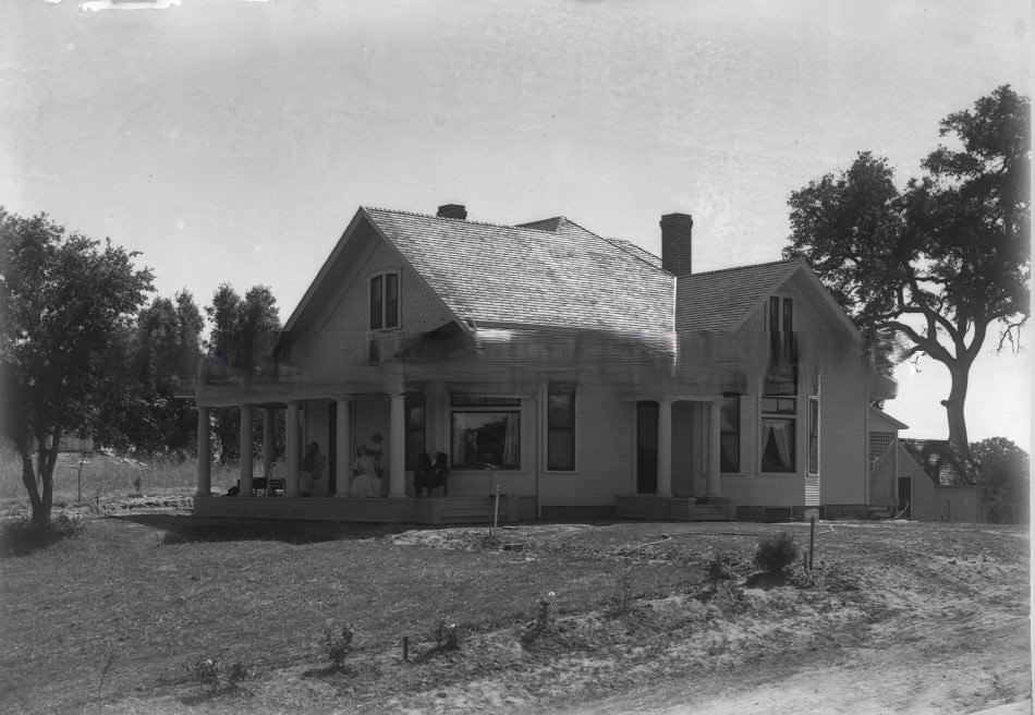 Exterior view of three people sitting on the porch of a house in Fair Oaks, 1890