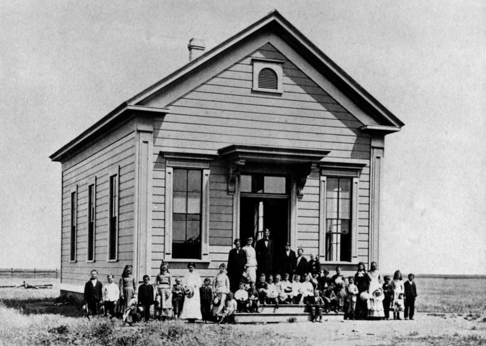 Students and teachers standing in front of a school building, 1890