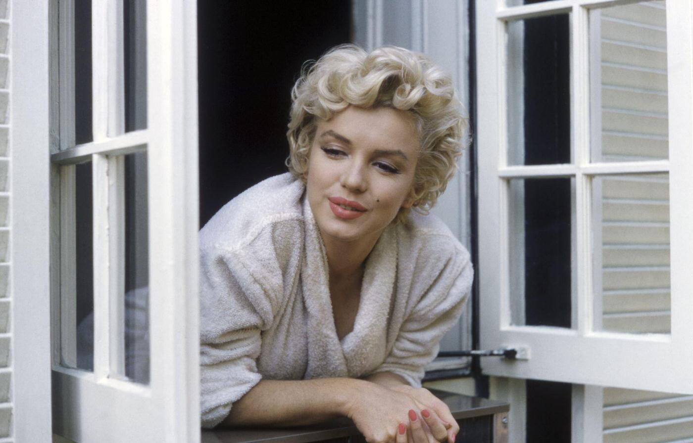 Marilyn Monroe leaning out of a window in her bathrobe in 1954 during the filming of "The Seven Year Itch" in New York