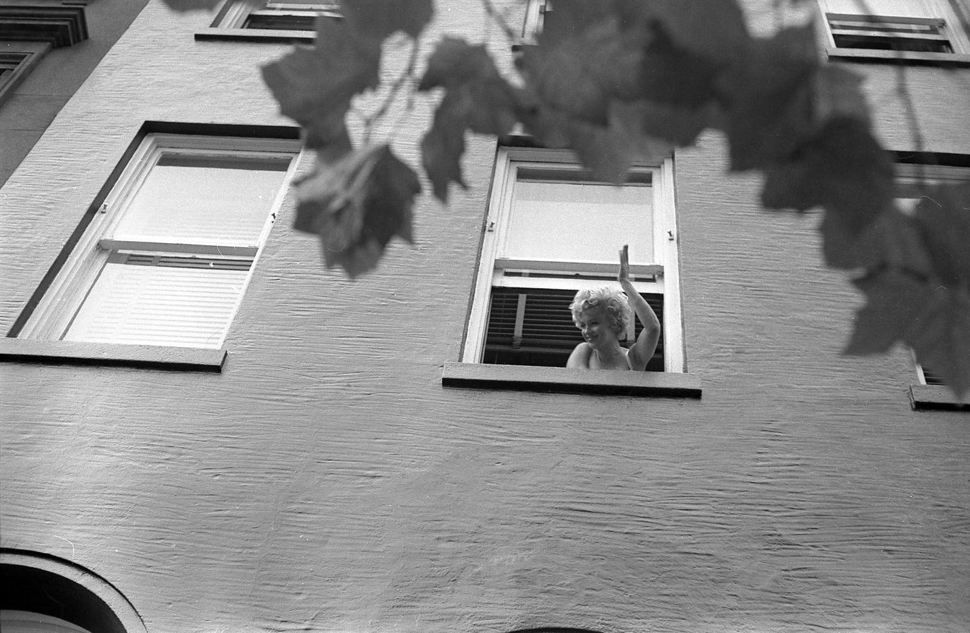 Marilyn Monroe leans out of a window to wave in 1954 during the filming of "The Seven Year Itch" in New York