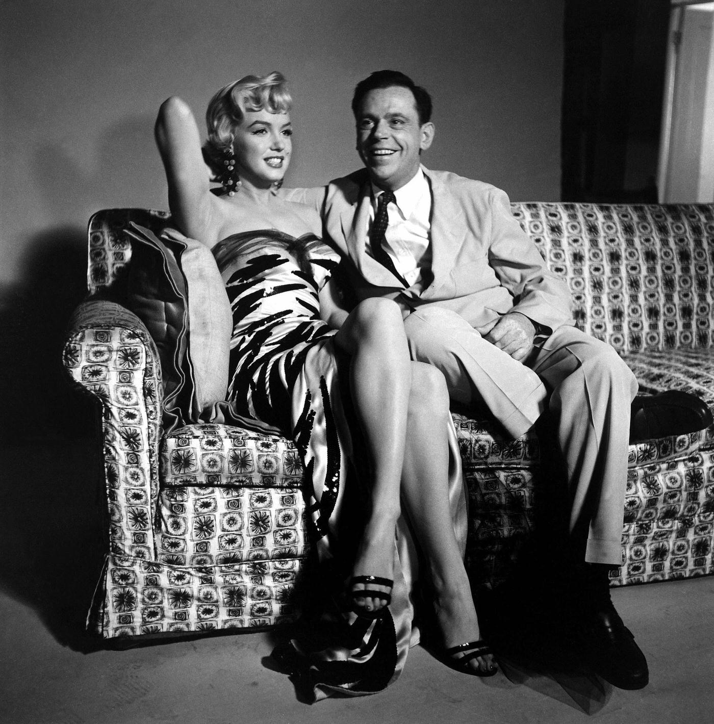 Marilyn Monroe wearing a tiger-striped dress sits next to co-star Tom Ewell in 1954 during the filming of "The Seven Year Itch"