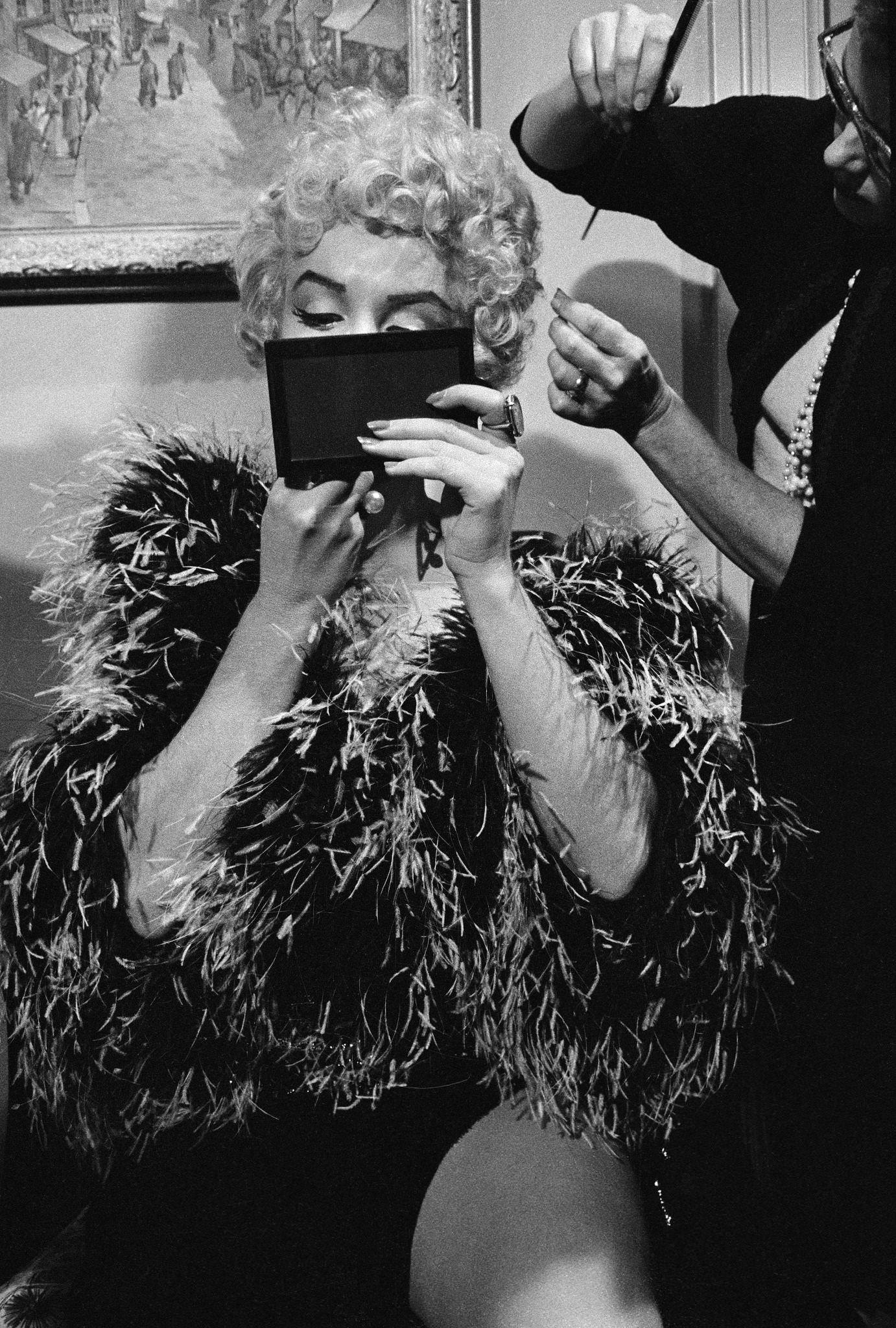 Marilyn Monroe wearing a feather boa puts on makeup to prepare for a scene during the filming of "The Seven Year Itch" in 1954