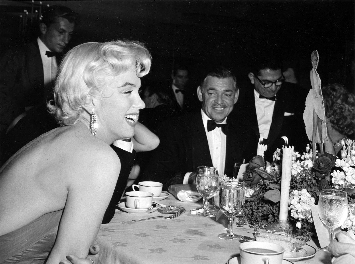 Marilyn Monroe with Clark Gable and newspaper columnist Sidney Skolsky at the wrap party for the filming of "The Seven Year Itch" at Romanoff's Restaurant in 1954