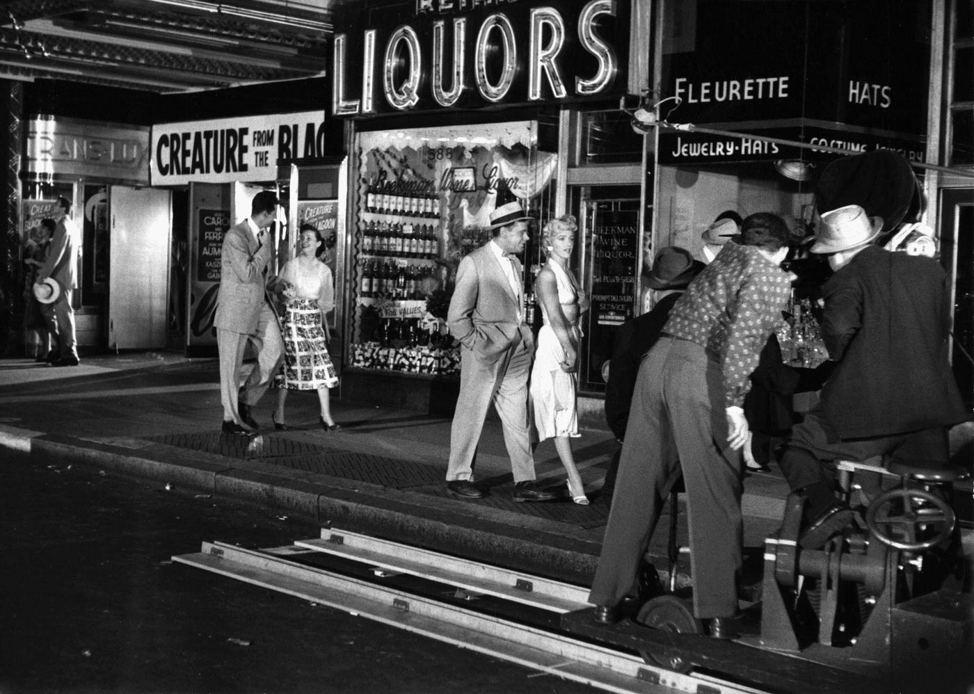 Marilyn Monroe walking with Tom Ewell in front of the Trans-Lux Theater on the corner of 51st Street and Lexington Avenue while filming the famous skirt-blowing scene for "The Seven Year Itch" in September, 1954