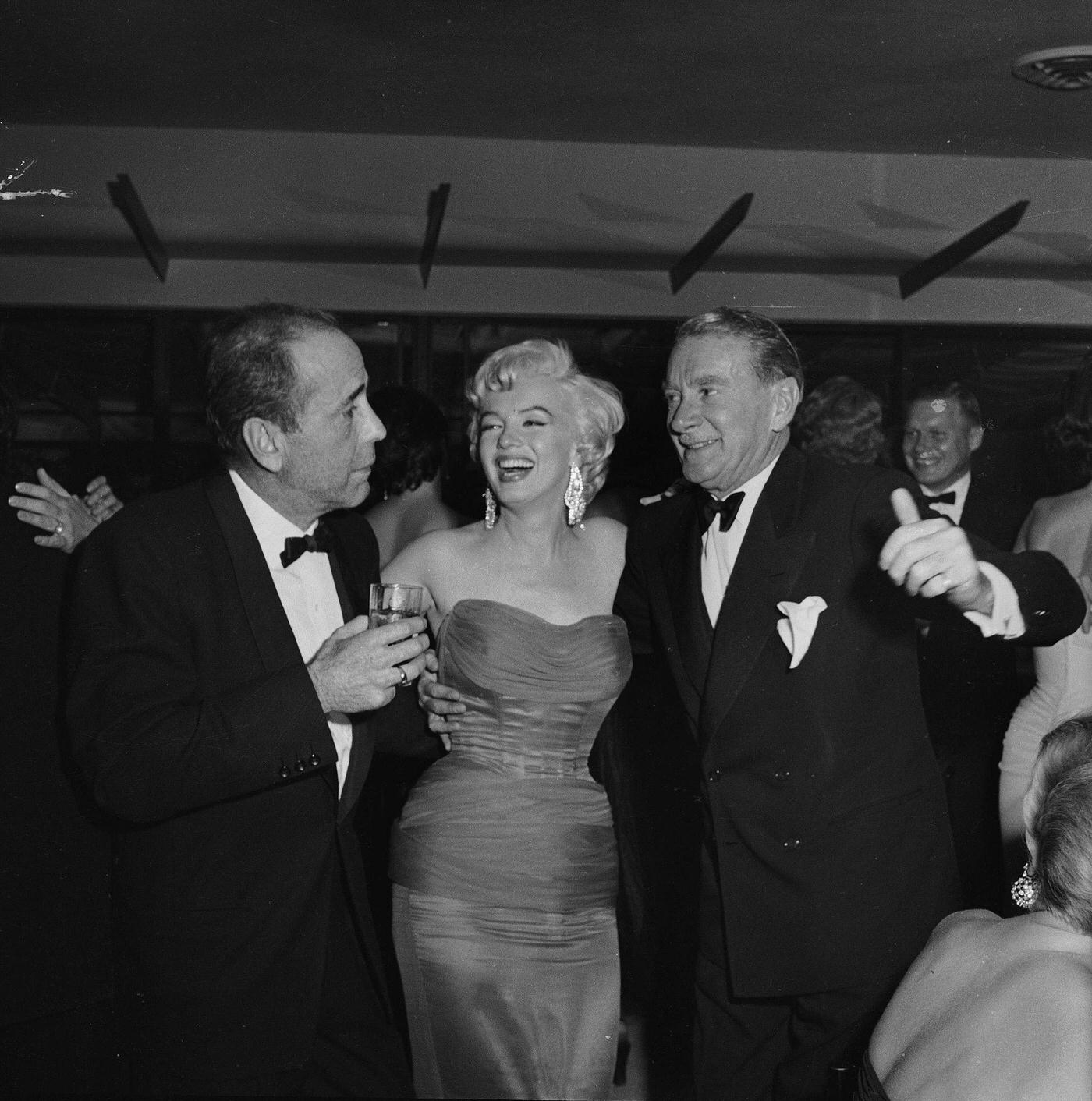 Marilyn Monroe with actors Humphrey Bogart and Clifton Webb at the wrap party for the filming of "The Seven Year Itch" at Romanoff's Restaurant in 1954