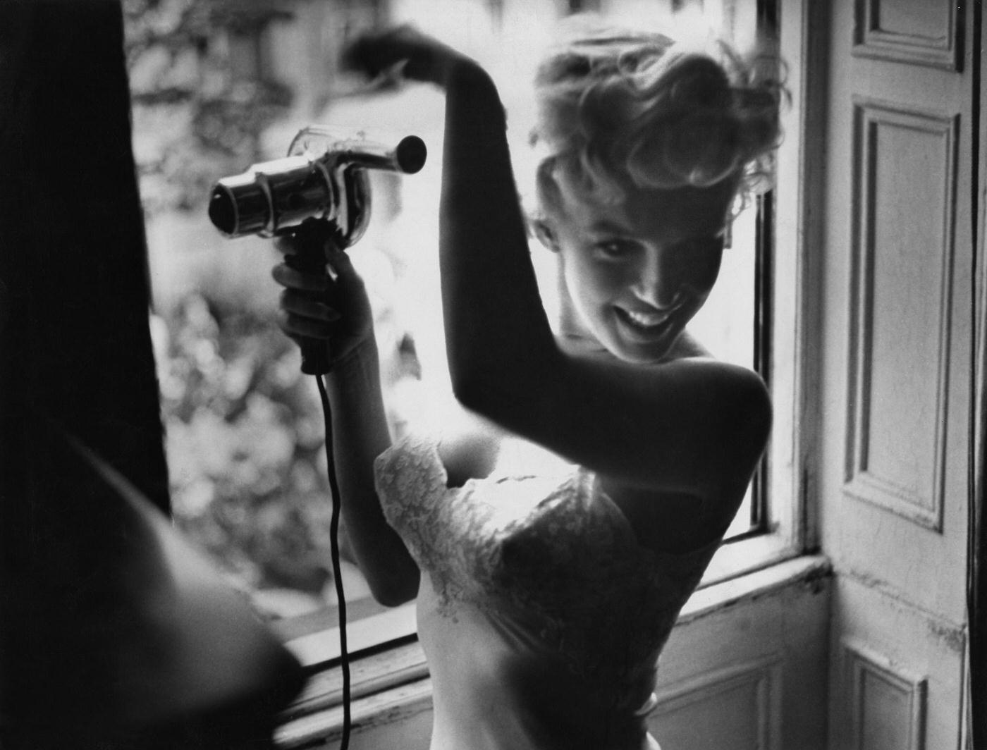 Marilyn Monroe blow-dries her hair in front of an open window in 1954 during the filming of "The Seven Year Itch" in New York