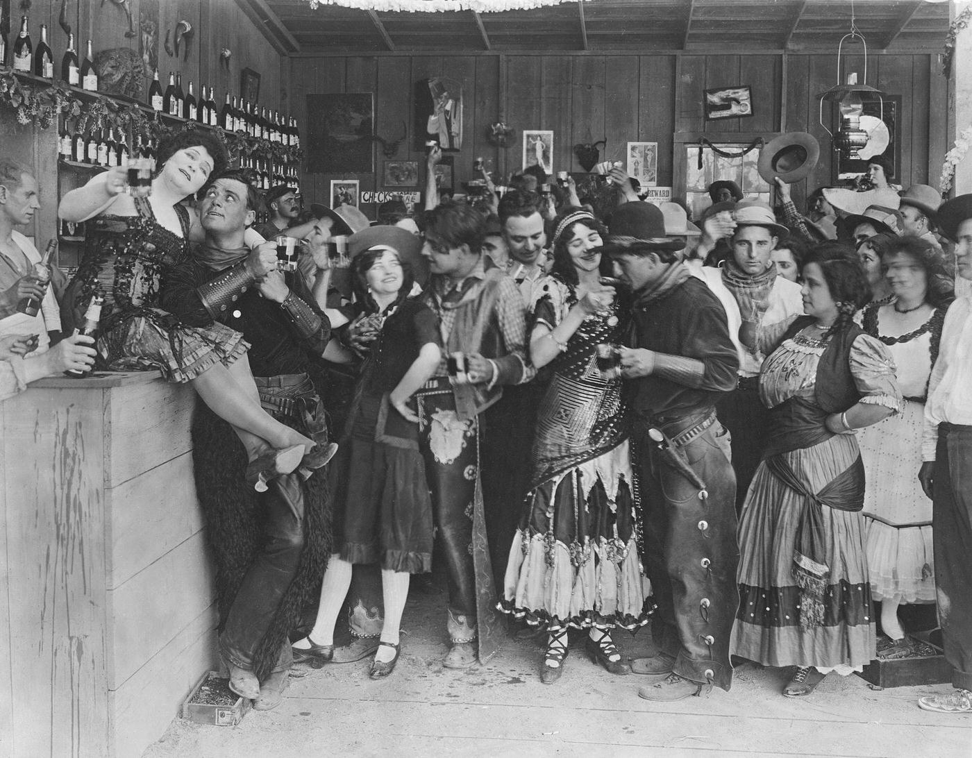 Cowboys and bar girls whoop it up in a still from an old silent Western.