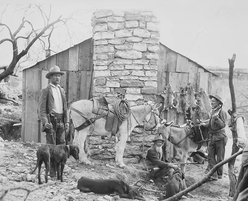 Trappers and hunters, including the Crab Tree boys and their father, with their dogs and burrows, are seen in Brown’s Basin, Arizona in this photograph from an unknown date.