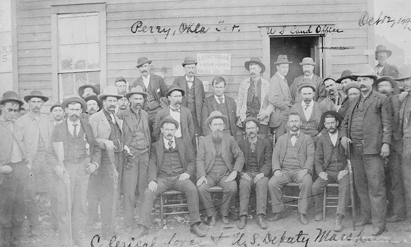 U.S. Deputy Marshals are seen posing with the clerical force in Perry, Oklahoma in 1893.