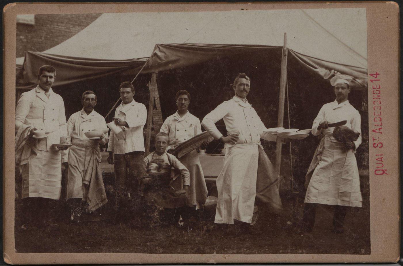 A group of cooks who travel with the Pawnee Bill Wild West Show display their wares for a photographer around 1900 during a tour of France, 1900