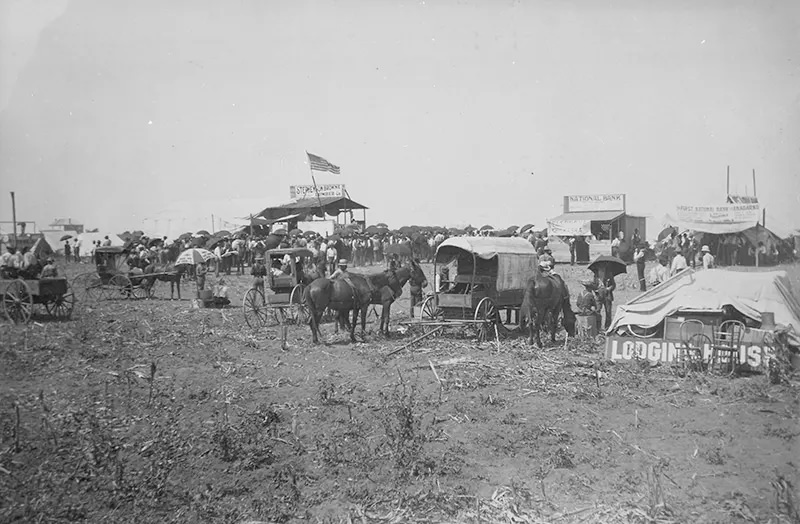 Anadarko Townsite, August 8, 1901: Auction in progress in lumber company booth, with temporary bank buildings and the beginnings of a lodging house nearby.