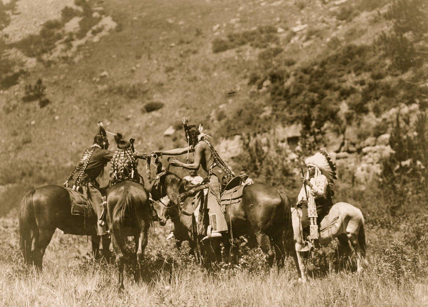 Crow men on horseback apparently involved in an exchange, 1905