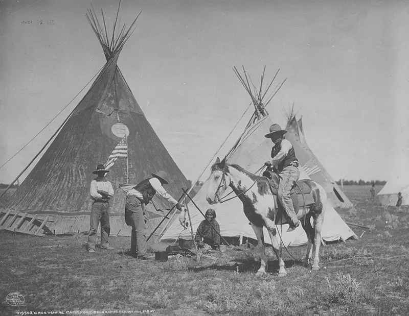 Gros Ventre Camp, Fort Belknap Reservation: A dog is being roasted over the cooking pot at Fort Belknap Reservation, Montana in 1906.