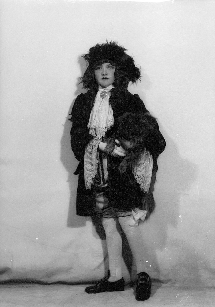 Portrait of a performer in costume holding a small dog