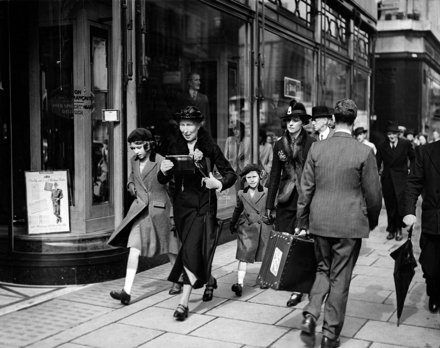 Elisabeth II, with her sister Princess Margaret Rose and governess on a walk in London.