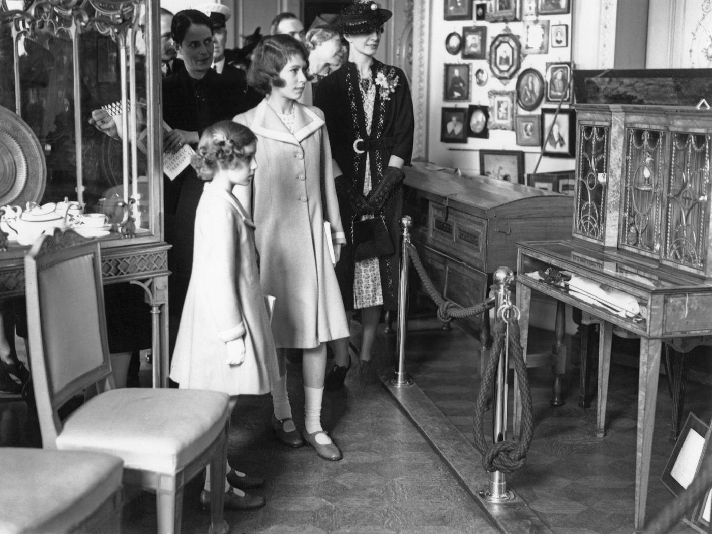 Princesses at Exhibition: Princesses Elizabeth (later Queen Elizabeth II, centre) and Margaret at an exhibition of royal treasures at 145 Piccadilly, London, 28th July 1939.