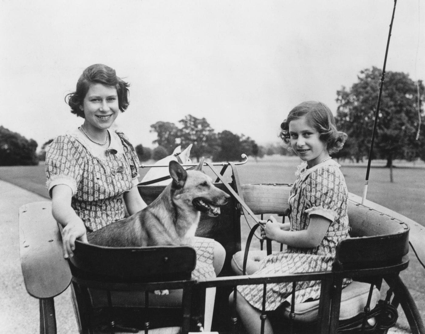 Princess Elizabeth (now Queen Elizabeth II, left) and her younger sister Princess Margaret Rose (1930-2002) in a carriage in the grounds of the Royal Lodge in Windsor Great Park, 4th July 1940.