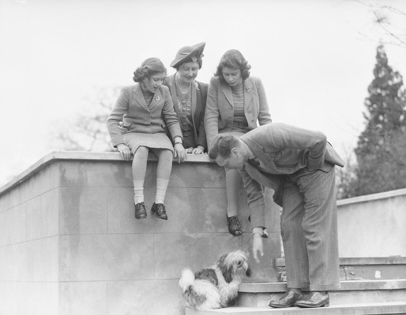 King George VI pets a dog while the Queen Elizabeth, Princess Elizabeth and Princess Margaret look on at the Royal Lodge in Windsor Castle, England on April 11, 1942.