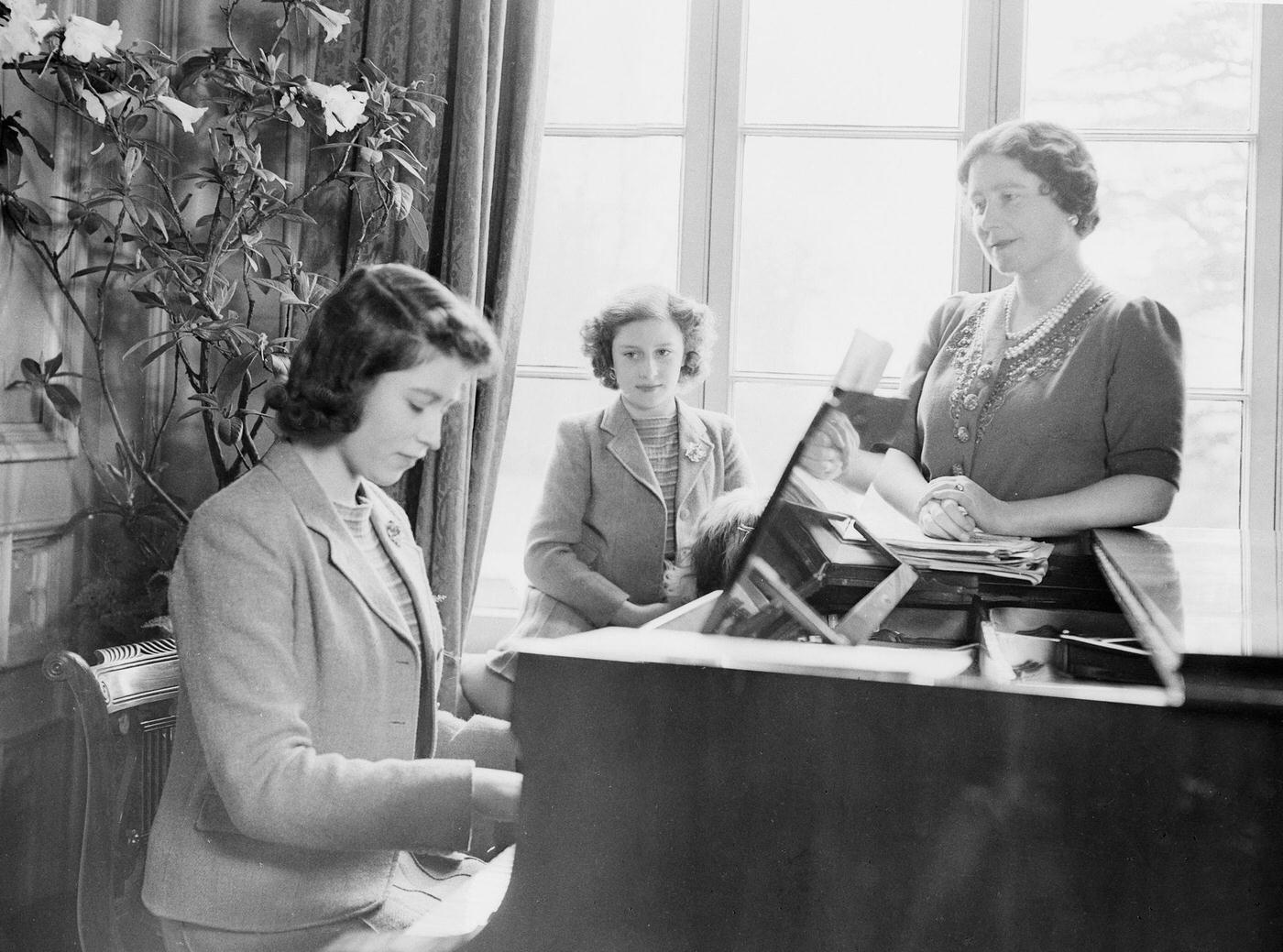 Princess Elizabeth plays the piano as Queen Elizabeth and Princess Margaret look on at the Royal Lodge in Windsor Castle, England on April 11, 1942.