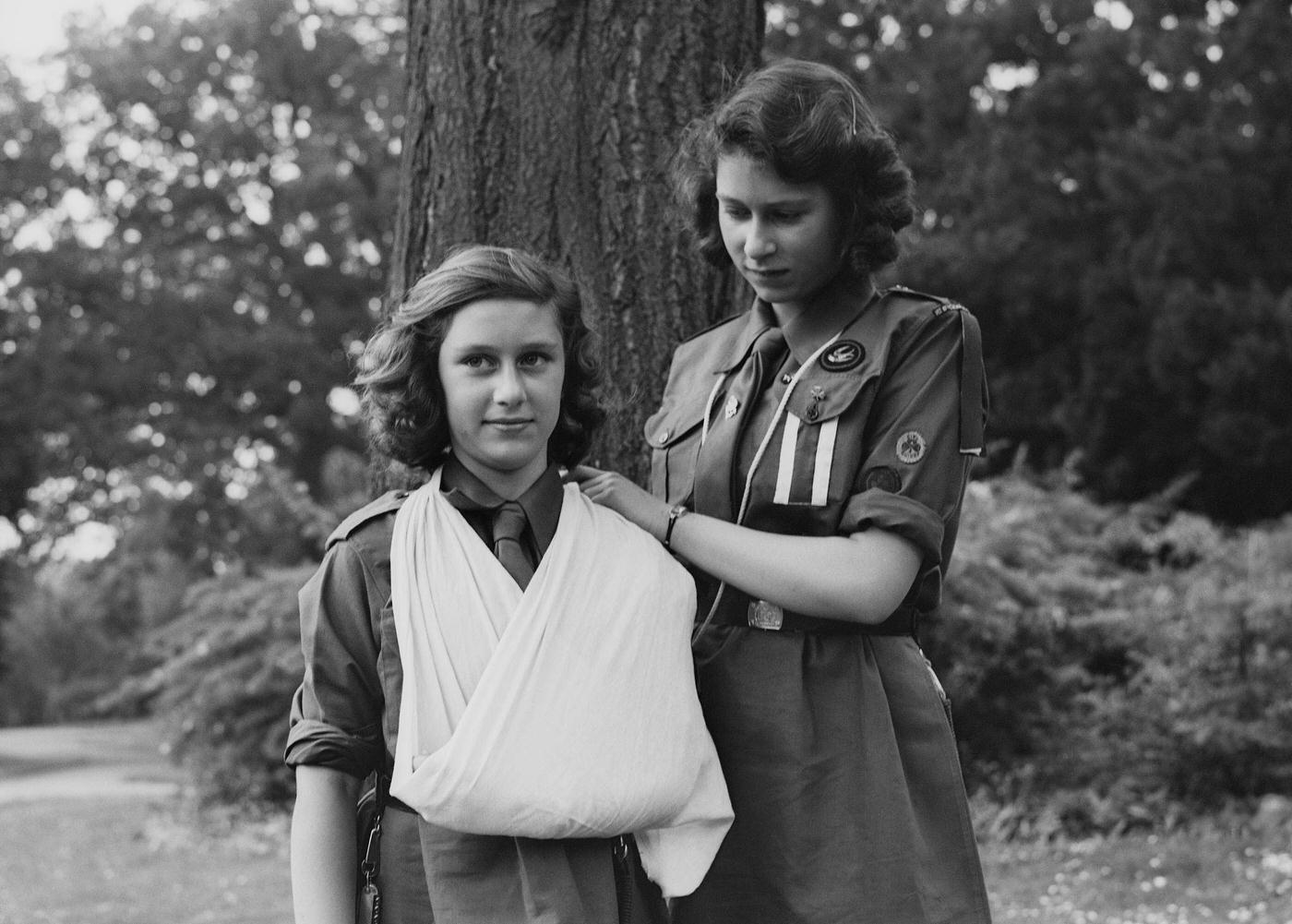 Princess Elizabeth places Princess Margaret's arm in a sling as part of the girl guides in Frogmore, Windsor, England on April 11, 1942.