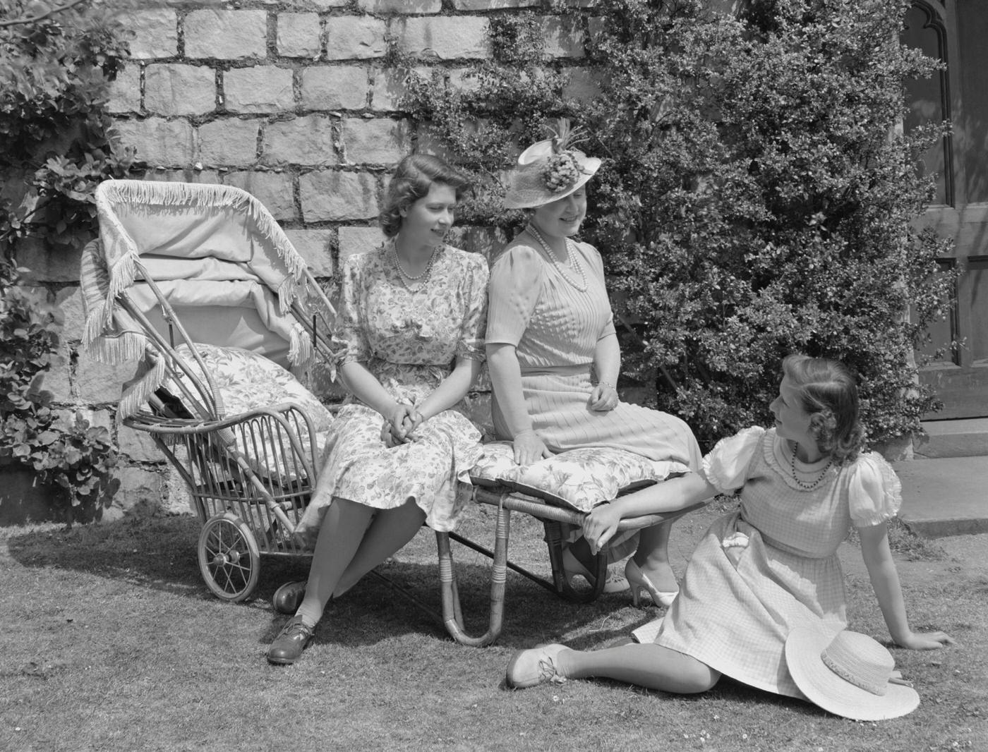Princess Elizabeth and Queen Elizabeth, The Queen Mother, seated on a sun lounger with Princess Margaret seated on the grass in the garden at Windsor Castle, 1944