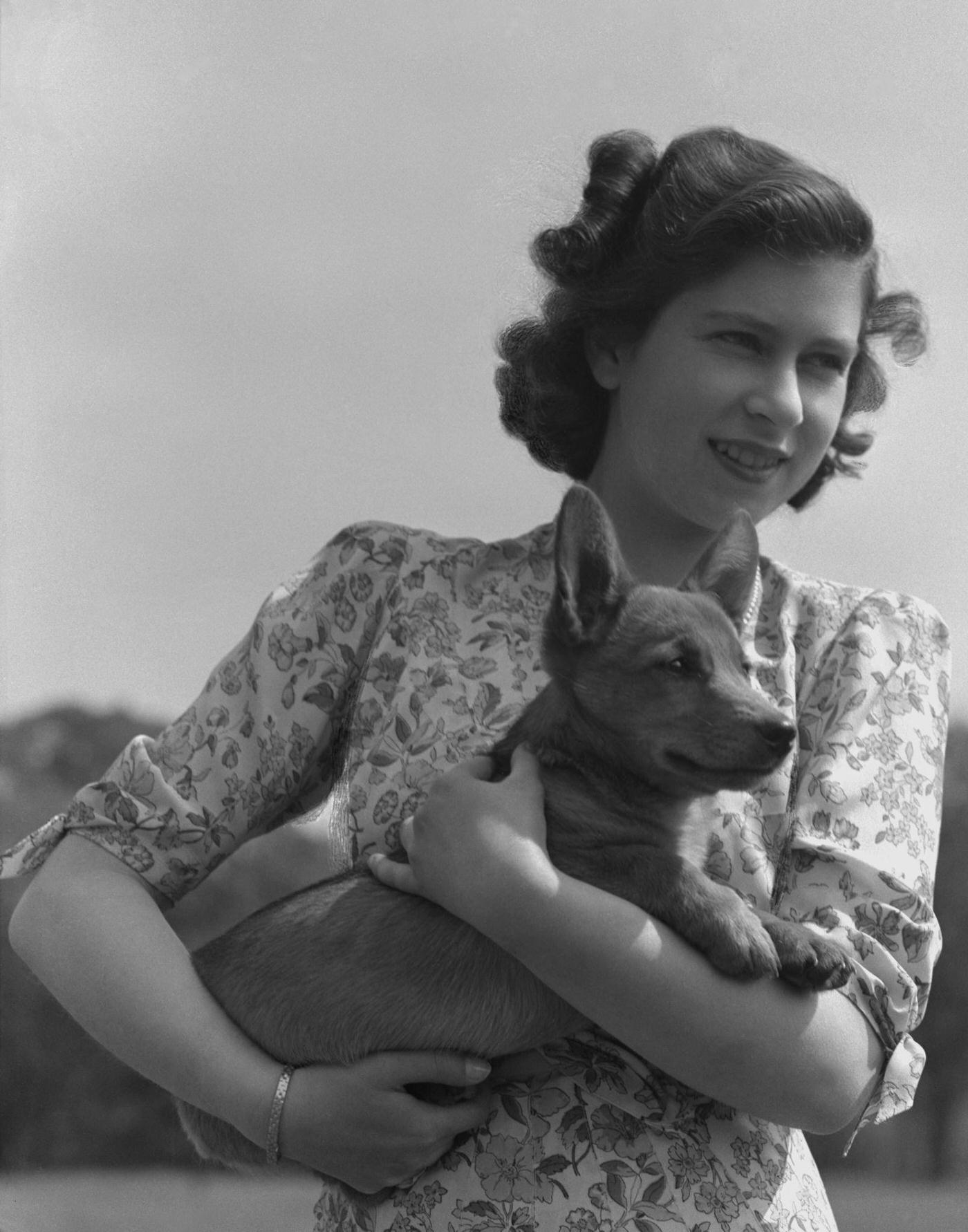 Princess Elizabeth pictured holding a corgi in the grounds of Windsor Castle, 1944