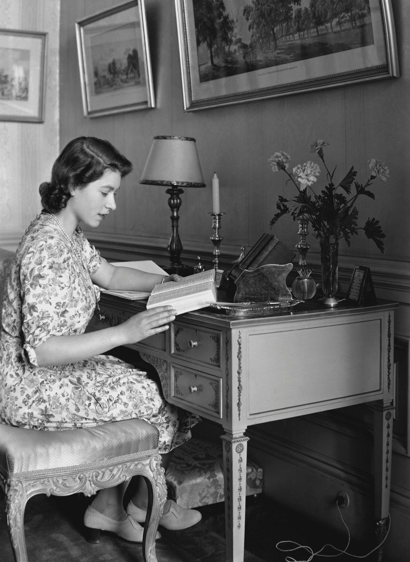 Princess Elizabeth pictured seated at a desk reading a book at Windsor Castle, 1944