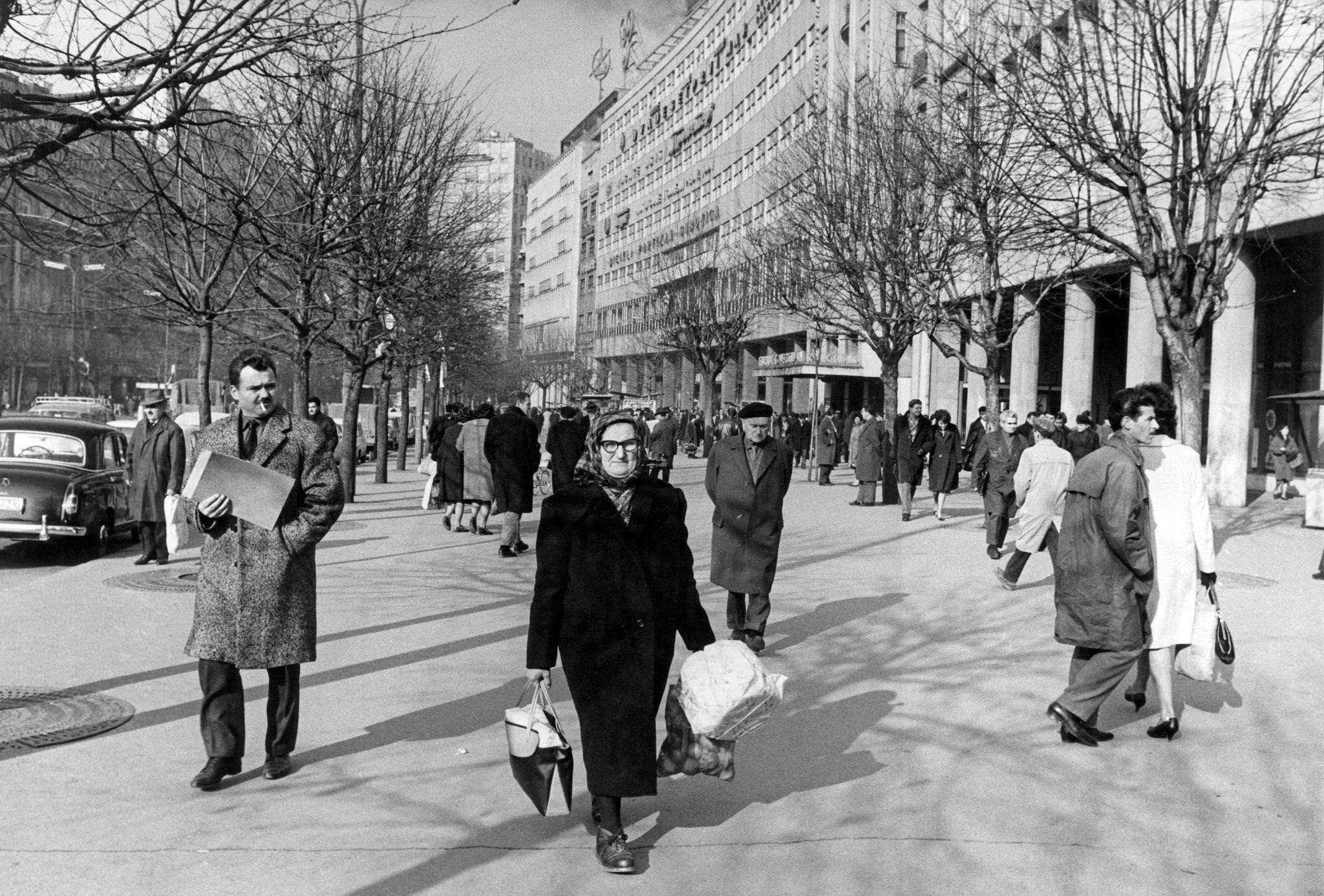 An elderly Yugoslav woman going back home carrying tote bags in Terazije square. Belgrade (Yugoslavia), December 1965