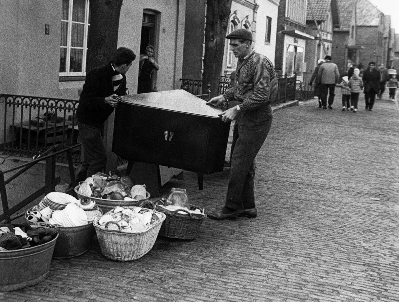 Two men carrying furniture in Finkenwerder during the North Sea Flood of 1962 in Hamburg, West Germany